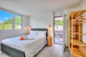 Habitación de hotel con cama, armario de madera, balcón y vistas, además de una ventana.