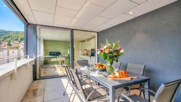 A modern dining area with a table set for two, a vase of flowers, and a bowl of fruit.