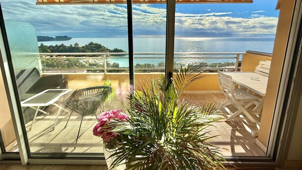 A balcony with a view of the sea, a table, chairs, and a potted plant. - MONACO Fantastic seaview - 2 bedrooms- 110m² - AC (Roquebrune Cap Martin)