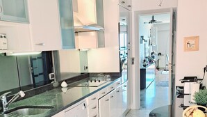 A modern kitchen with white cabinetry, a granite countertop, and a stainless steel sink. - MONACO Fantastic seaview - 2 bedrooms- 110m² - AC (Roquebrune Cap Martin)