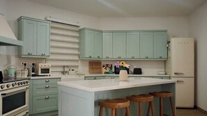 Eine Küche mit hellblauen Schränken, einer weißen Arbeitsplatte und Holzstühlen.