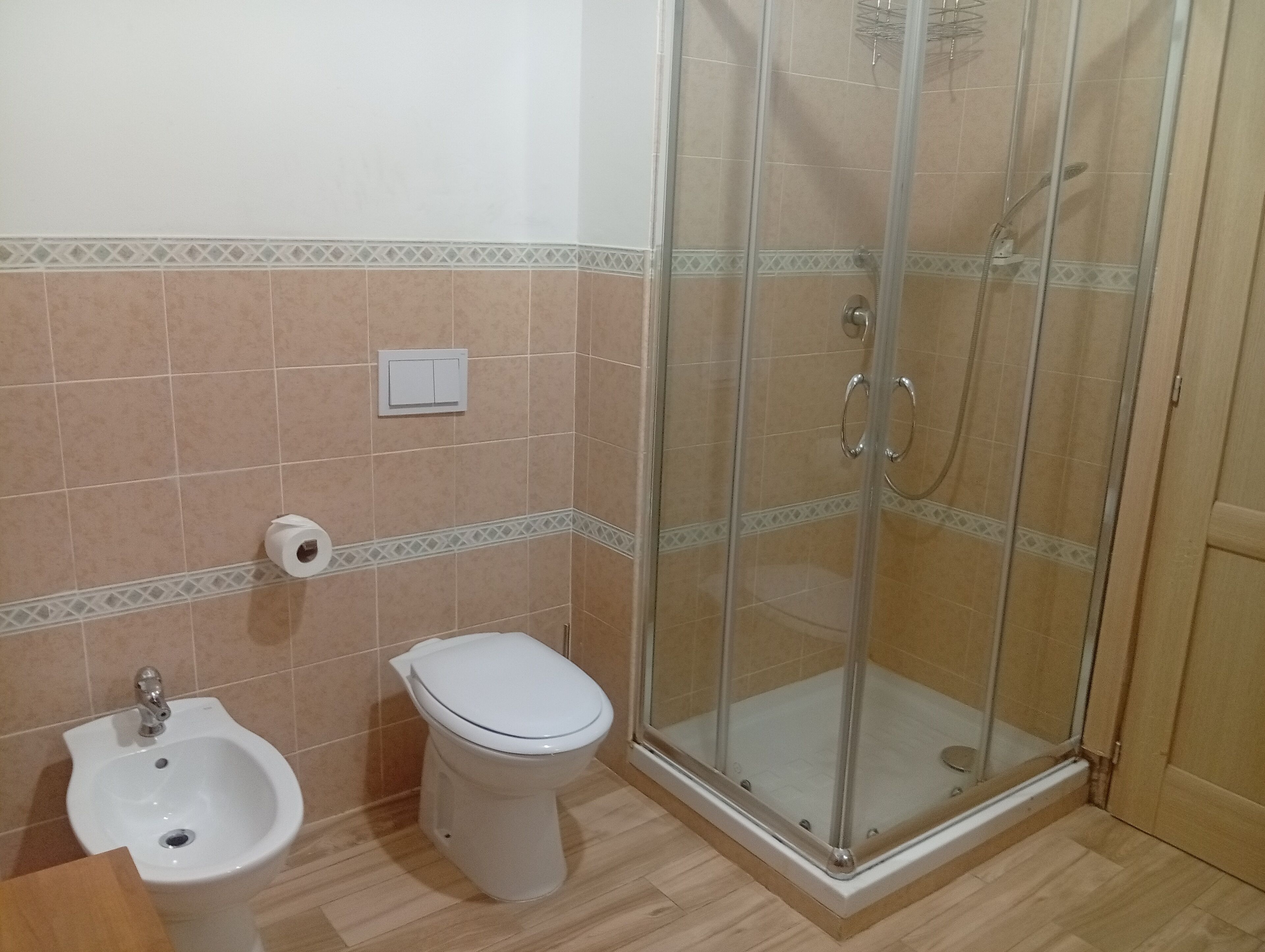 A bathroom with a bidet, toilet, and glass-enclosed shower.
