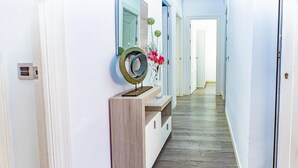 A hallway with a wooden console table, a mirror, and a vase with flowers.