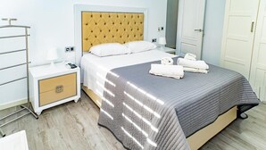 A hotel room with a bed, bedside tables, a wardrobe, and a mirror.