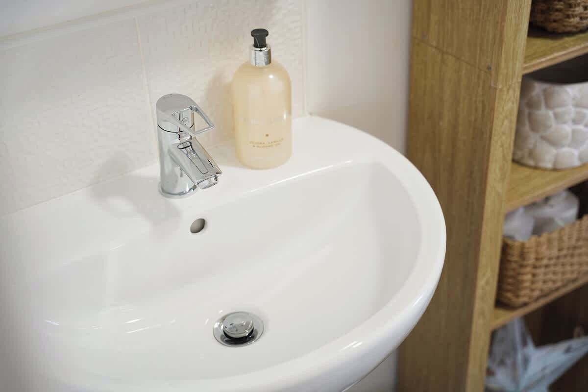 A white bathroom sink with a chrome faucet and a soap dispenser.