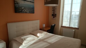 A bedroom with a bed, a desk, a chair, a window, and a painting on the wall. - Between vineyards and estuary, discover Walter's winery (Semillac)