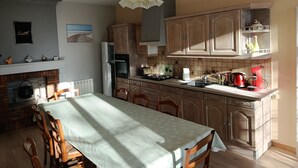 A kitchen with wooden cabinets, a dining table, and a hanging light fixture. - Between vineyards and estuary, discover Walter's winery (Semillac)