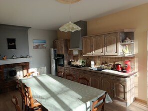 A kitchen with wooden cabinets, a dining table, and a hanging light fixture. - Between vineyards and estuary, discover Walter's winery (Semillac)