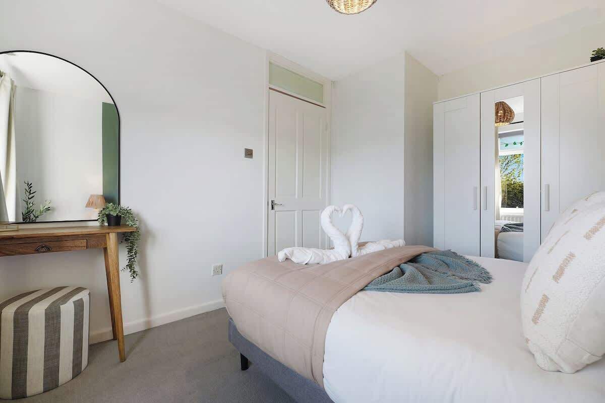 A bedroom with a bed, a desk, a mirror, a wardrobe, and a door.