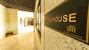 A corridor with a sign for 'Coffee House Wonder Properties.' - Cozy,all-equipped 1-bedroom apartment with cafe,gym &minimart in Uptown Nairobi. (Nairobi)