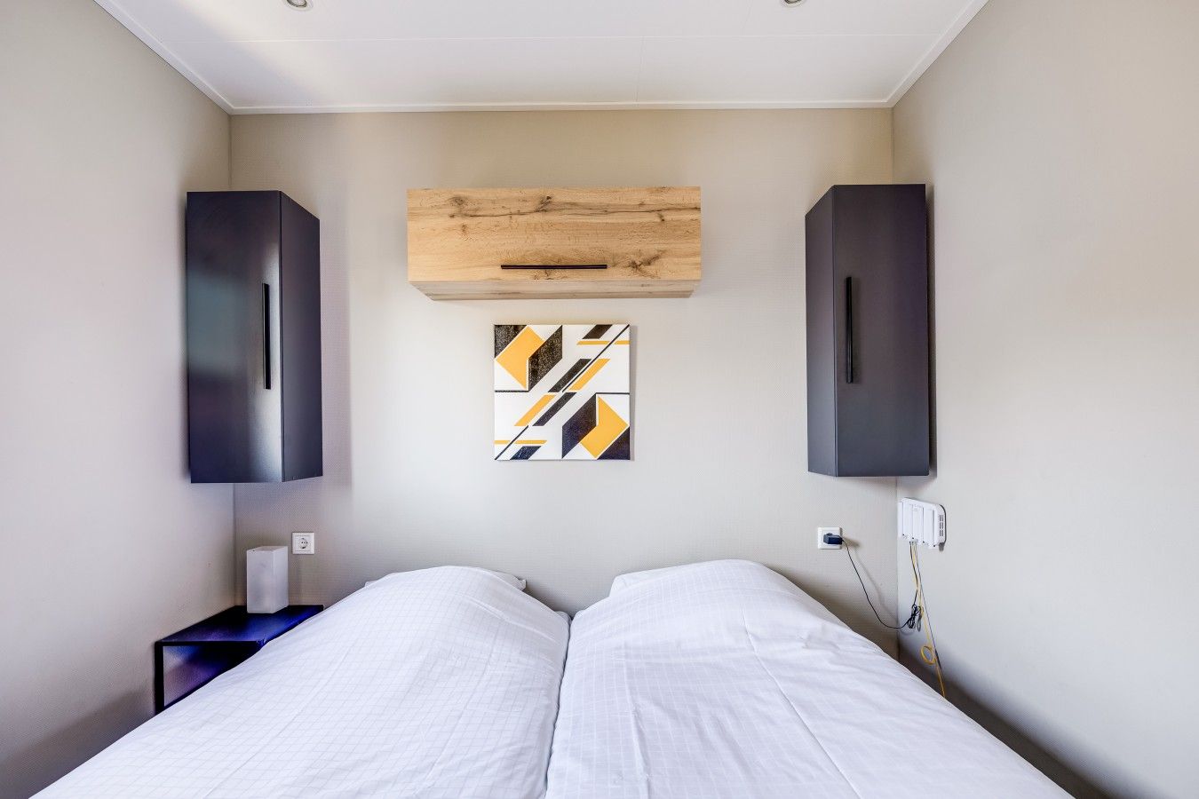 Une chambre d’hôtel comprenant un lit, deux armoires, une prise de courant et une œuvre d’art accrochée au mur.