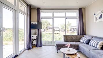 A modern living room with a grey sofa, a small round table, and a flat-screen TV.
