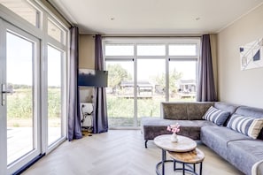 A modern living room with a grey sofa, a small round table, and a flat-screen TV.