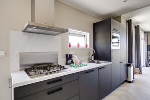 Una cocina moderna con estufa a gas, cafetera y lavaplatos.