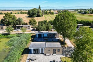 Een moderne woonwijk met meerdere huizen, een groot open veld en een waterpartij op de achtergrond.