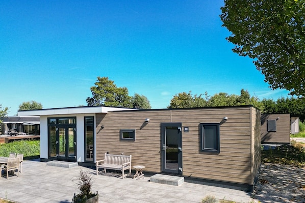 A modern, single-story building with a flat roof, a front door, and a small window.