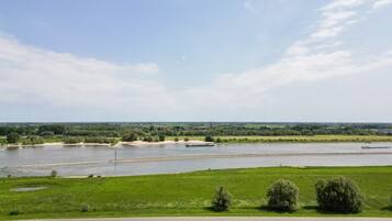 Ein Fluss mit einer Brücke, grünen Feldern und blauem Himmel.