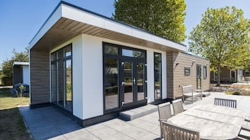 Een modern huis met een patio, grote schuiframen en een houten terras.