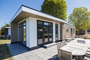 Una casa moderna con un patio, puertas correderas de vidrio y una terraza de madera.