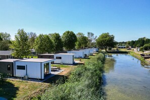 Una hilera de casas móviles modernas y blancas con un canal al frente.