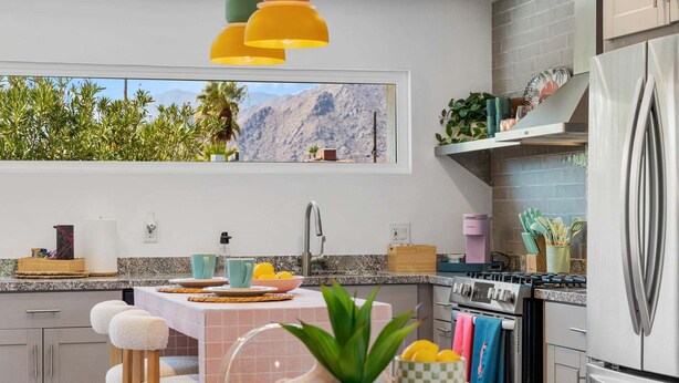 Een moderne keuken met uitzicht op bergen, een roestvrijstalen koelkast en een eethoek met een tafel en stoelen.