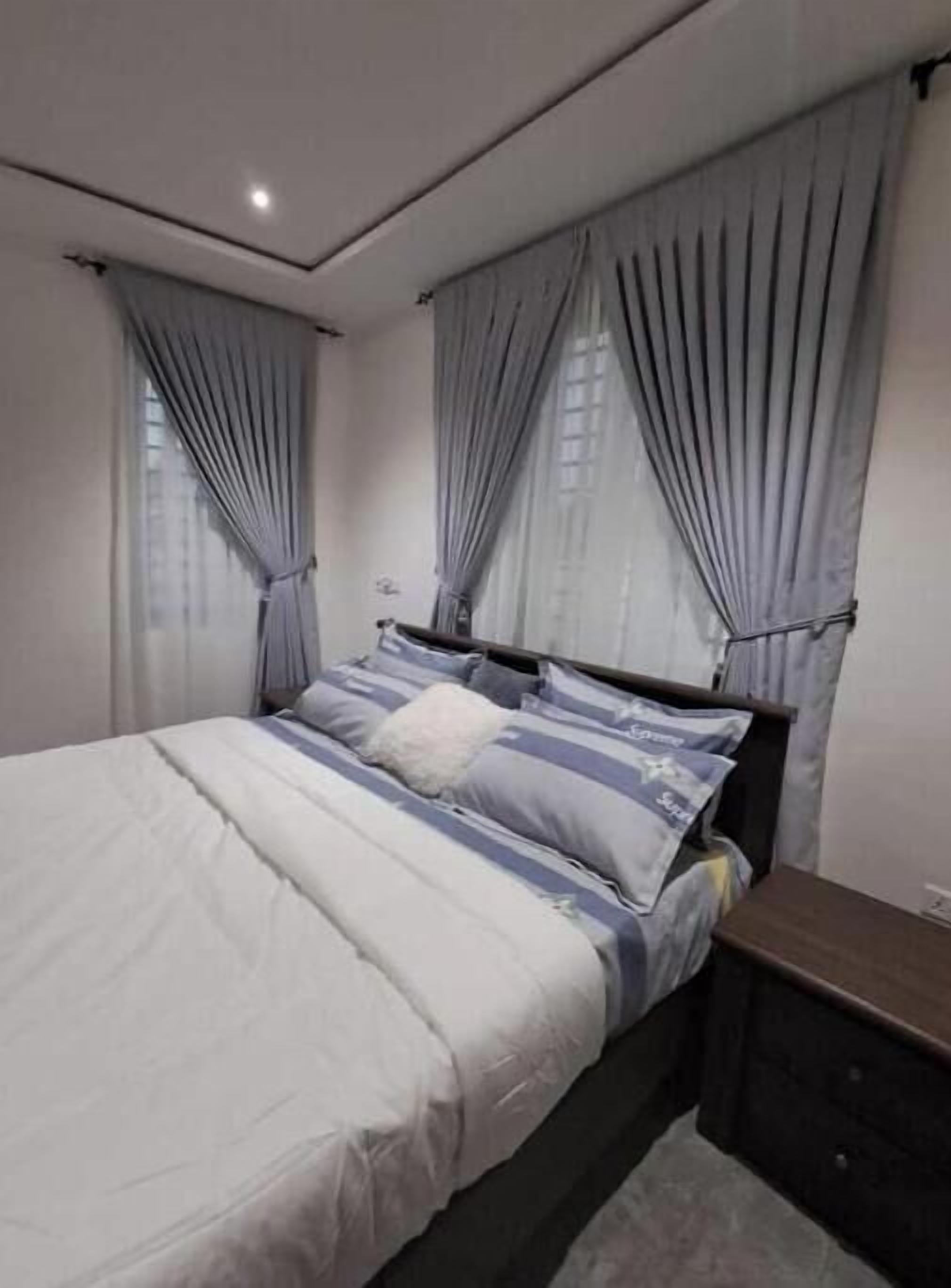Un dormitorio con cama, cortinas, mesita de noche y cómoda.