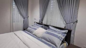 Un dormitorio con cama, cortinas, mesita de noche y cómoda.