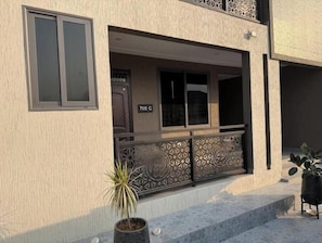 A building with a numbered address, a balcony with decorative railings, and a potted plant.