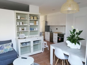 Un espace de vie compact comprenant un coin cuisine, un espace repas et un canapé.