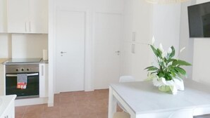 A kitchen with white cabinets, a stove, and a dining table with a plant.