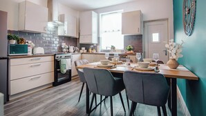 A modern kitchen with a dining area, featuring a stove, microwave, cabinets, and a dining table set for four.