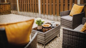 Wicker furniture, a glass table, and a wooden fence in an outdoor setting.