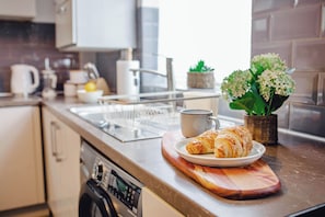 A kitchen counter with a plate of croissants, a mug, and a potted plant. - Golden Aqua Haven Retreat | Free Parking | 14PPL (Sheffield)