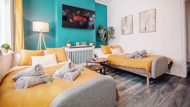 A hotel room with two beds, a TV, a bedside table, and a plant.