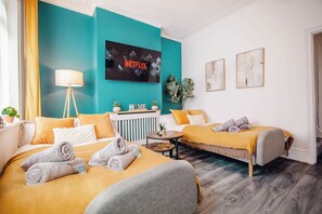 Ein Hotelzimmer mit zwei Betten, einem Fernseher, einem Nachttisch und einer Pflanze.