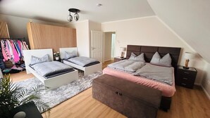A bedroom with two beds, a wardrobe, a mirror, and a plant. - Last-minute for the trade fair: 4-room apartment just 7 minutes away! (Laatzen)