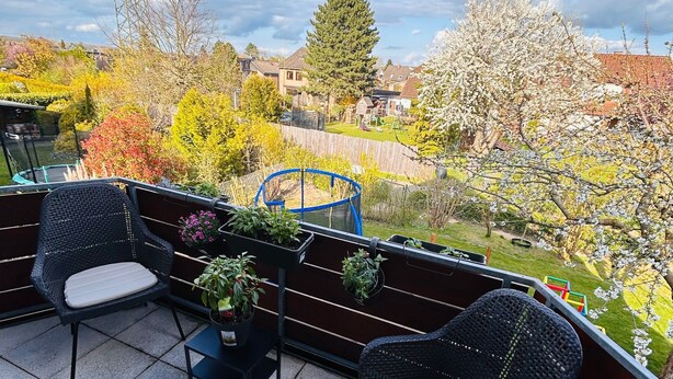 A balcony with two wicker chairs, a small table, and potted plants. - Last-minute for the trade fair: 4-room apartment just 7 minutes away! (Laatzen)