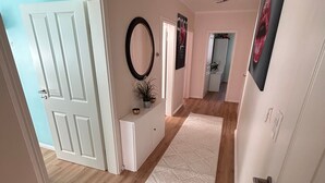 A hallway with a white door, a white console, a mirror, and a rug. - Last-minute for the trade fair: 4-room apartment just 7 minutes away! (Laatzen)