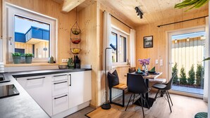 Moderni keittiö, jossa on valkoiset kaapit, musta työtaso sekä ruokailutila pöytineen ja tuoleineen.