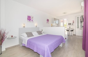 A bedroom with a bed, a bedside table, a small shelf, and a window. - Studio Talir with terrace (Dubrovnik)