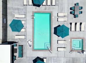 A rooftop pool area with a rectangular pool, lounge chairs, umbrellas, and a table. - Solace Luxury 1BR Retreat Pool Hot Tub Wifi (Reno)