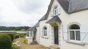 Een tweelaags huis met een stenen gevel, een klein voortuintje en uitzicht op het water.