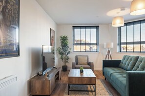 A living room with a sofa, coffee table, TV, and a potted plant. - City Point Aberdeen by Guestz (Aberdeen)