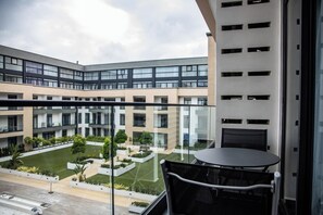 Ein modernes Gebäude mit Innenhof, einem Balkon mit Tisch und Stühlen sowie Blick auf die umliegende Architektur.