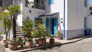 A white building with blue shutters and a tiled roof, surrounded by potted plants. - Apartment 'La Maison Des Artistes' with Wi-Fi and Air Conditioning (Mozzecane)
