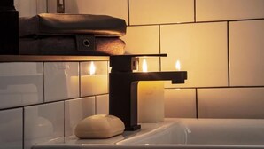 Un baño con bañera, una toalla, una vela y un jabonera.