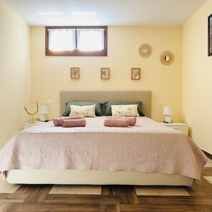 A bedroom with a bed, two bedside tables, a window, and wall decorations. - Apartamento Aurora (Orosei)