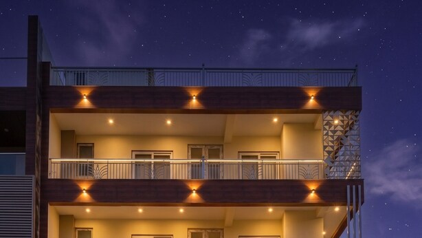 A multi-story hotel with balconies, a neon sign, and a well-lit entrance. - OnlyStay Snap Hotel (Noida)