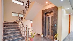 A hotel lobby with a marble staircase, a reception desk, and a glass elevator. - OnlyStay Snap Hotel (Noida)