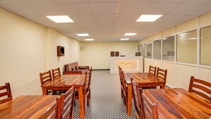 A conference room with a long table, multiple chairs, a small sofa, a wall-mounted fan, and a sign reading 'OnlyStay Hotel.' - OnlyStay Snap Hotel (Noida)